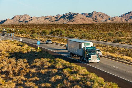 A large truck on a highway with a desert landscape